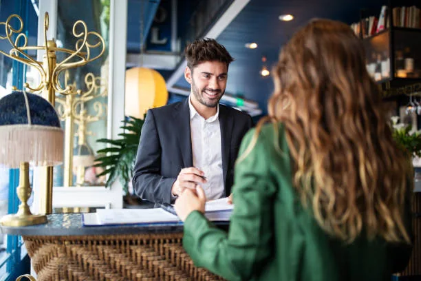 A man and a woman talking across a reception counter
