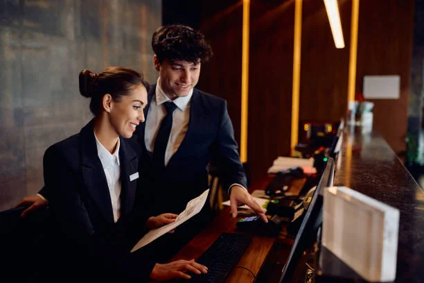Two receptionists looking at a computer and a document at the front desk