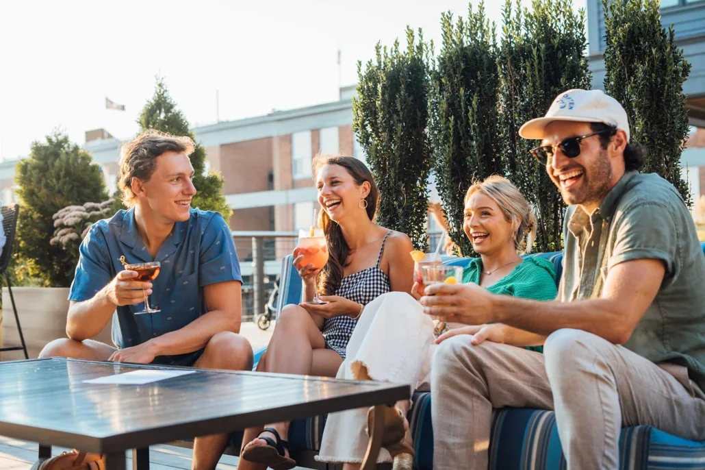 Four friends sitting on a terrace, chatting with drinks in their hands