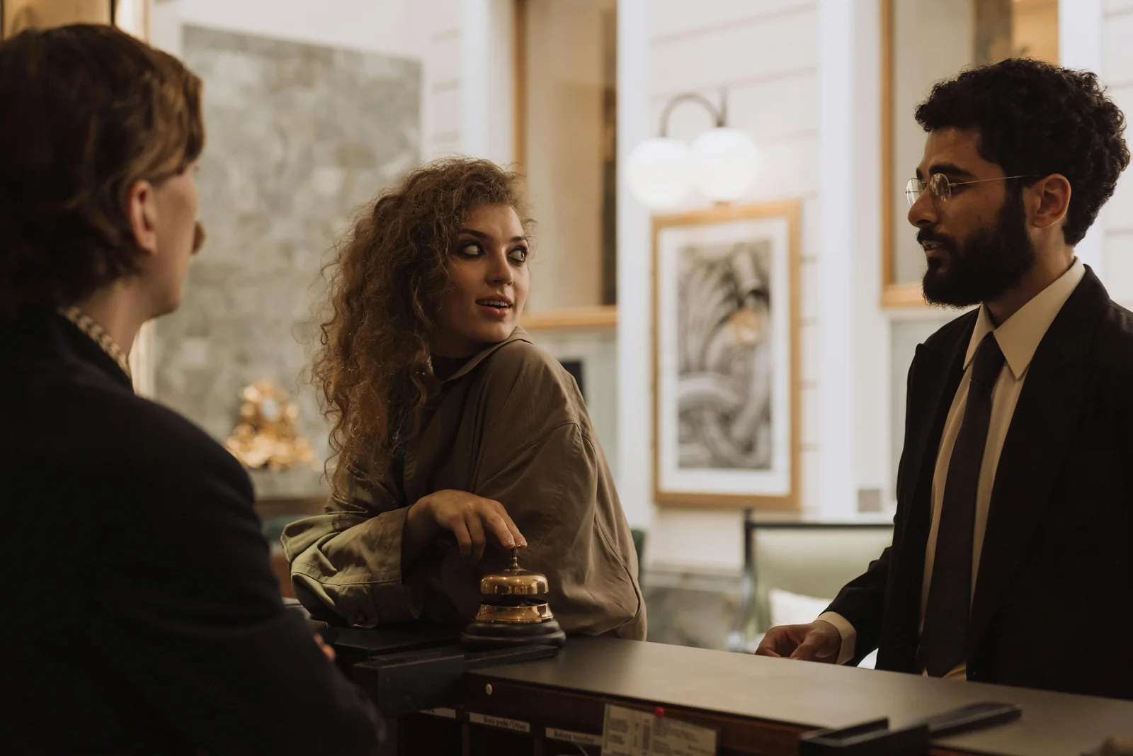Dos huéspedes conversan con una recepcionista en el mostrador de un hotel