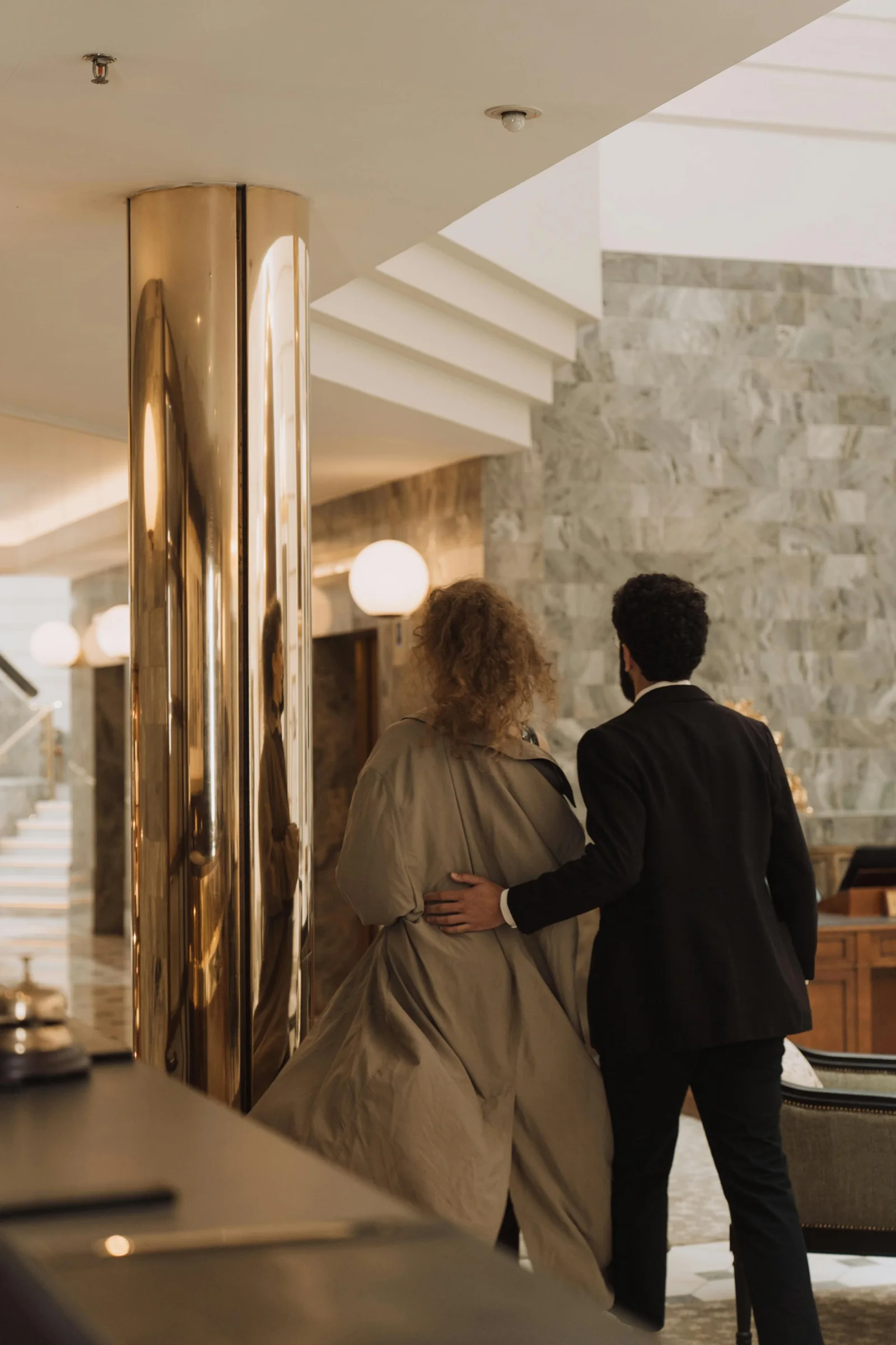 Two guests seen from behind walking through a hotel lobby