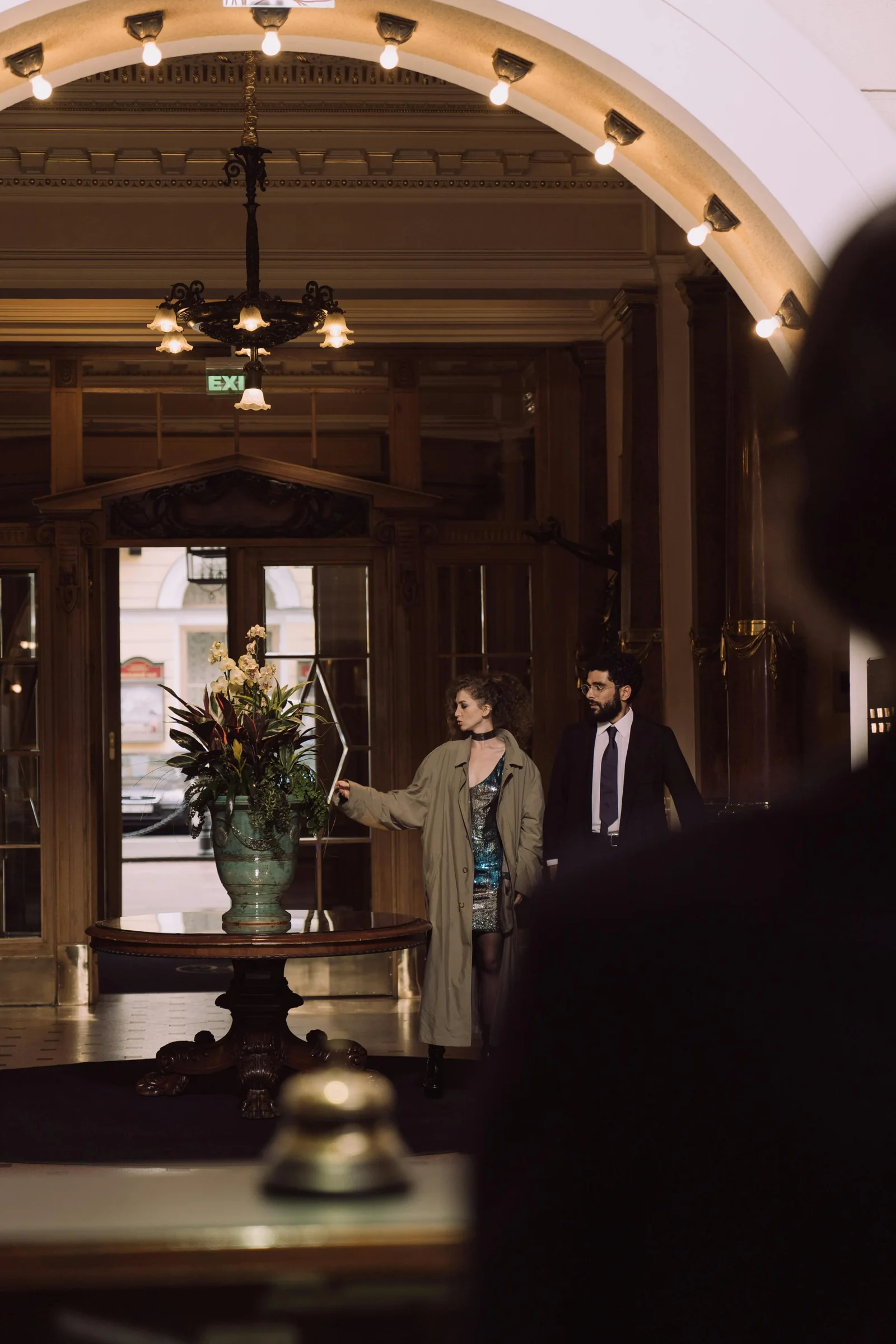 Two guests beside a table with flowers in a hotel lobby