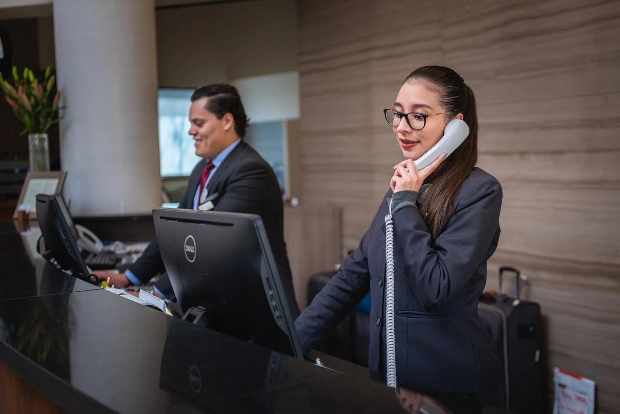 Recepcionista atendiendo una llamada telefónica frente a un ordenador