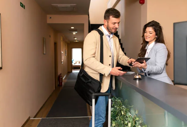 A guest with a suitcase looking at a tablet with a receptionist