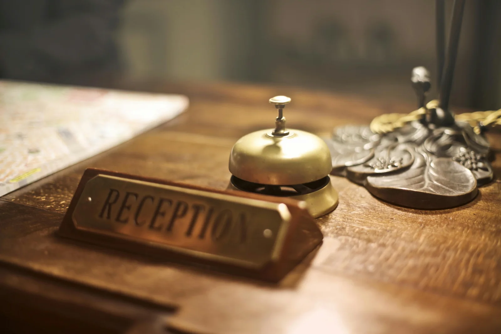 A brass bell beside a reception sign on a wooden counter