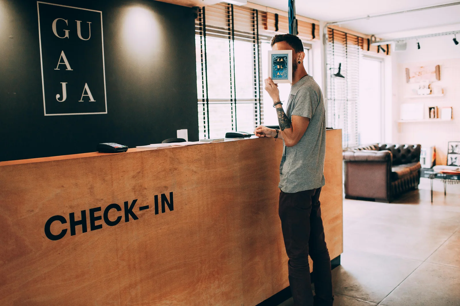 A man beside a check-in counter holding a small framed picture in front of his face